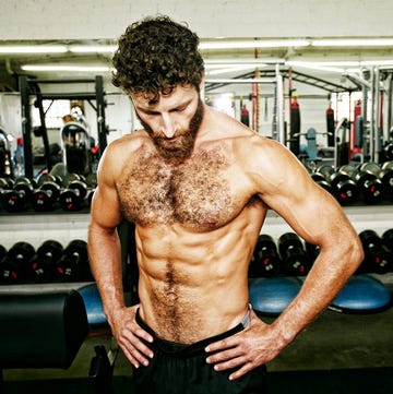 male athlete posing with a muscular physique in a gym setting
